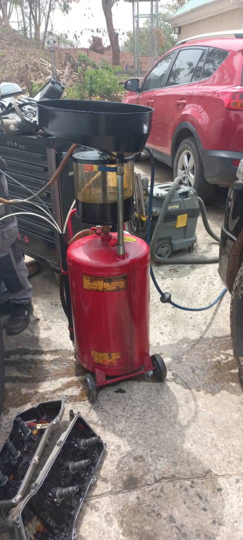 Red waste oil extractor in use at GTGAS workshop with vehicles in background