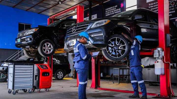 Two GTGAS technicians inspecting SUVs raised on hydraulic lifts