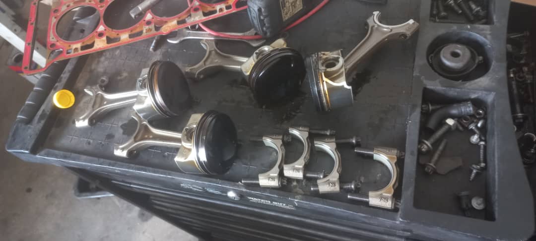 Engine pistons, connecting rods, and bearing caps laid out on workbench