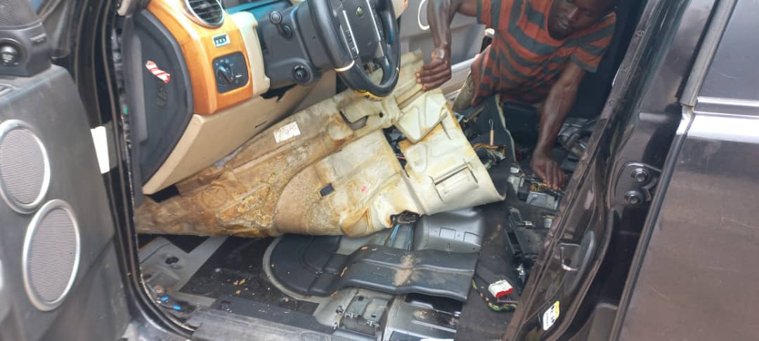 Technician removing damaged carpet and floor trim from an SUV interior