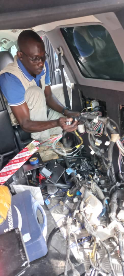Technician testing electrical components inside vehicle cabin
